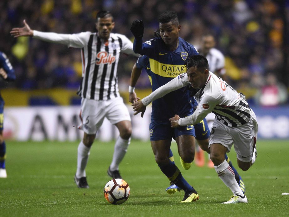 Angel Lucena (right) of Paraguay's Libertad, fights for the ball with Wilmar Barrios (center) of Argentina's Boca Juniors, during a Copa Libertadores soccer match in Buenos Aires, Argentina on Wednesday.