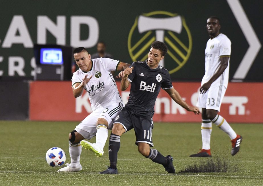 Vancouver Whitecaps' David Guzman (20) vies with Portland Timbers Nicolas Mezquida (11) for possession of the ball during an MLS soccer match in Portland, Ore on Saturday.