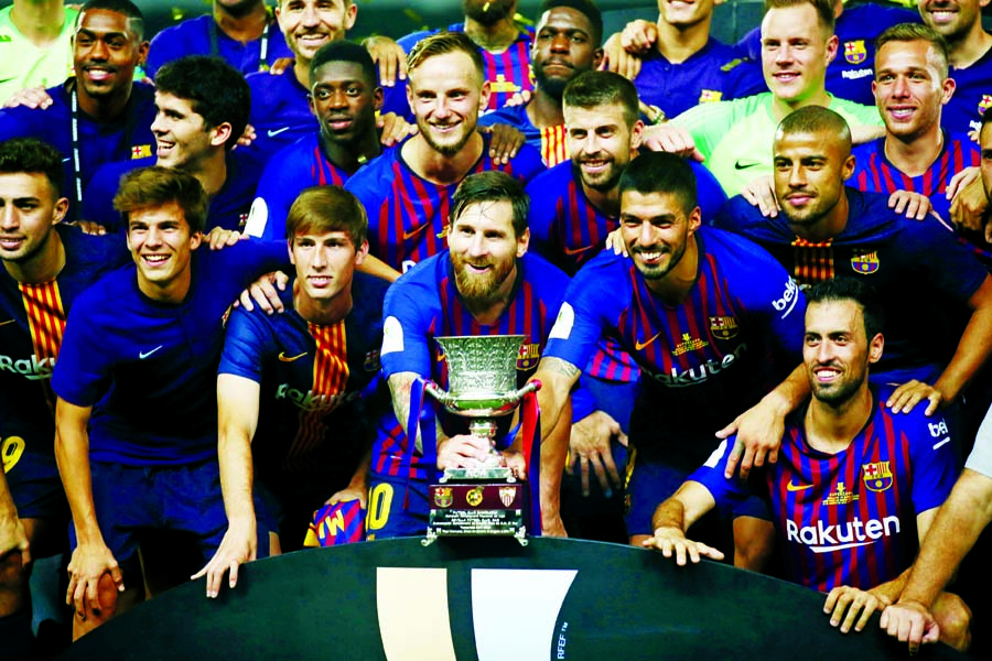 Barcelona players pose with the trophy after winning the Spanish Super Cup soccer match between Sevilla and Barcelona in Tangier, Morocco on Sunday. Barcelona won 2-1.