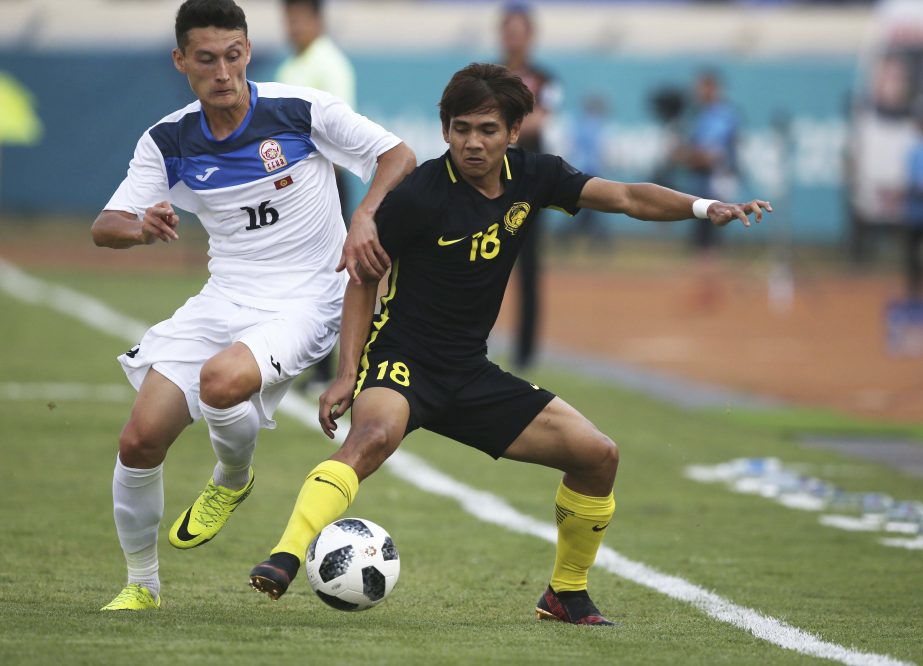 Malaysia's Muhammad Akhyar Abdul Rashid (right) battles for the ball with Kyrgyzstan's Eildiiar Sardarbekov during their men's soccer match between Kyrgyzstan and Malaysia at the 18th Asian Games at Si Jalak Harupat Stadium in Bandung, Indonesia on Wed
