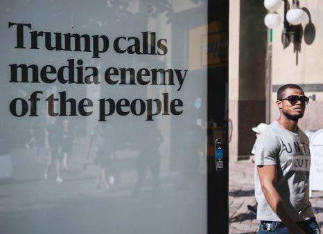 A man walks past an advertising board reading "Trump calls media enemy of the people" on the sidelines of a meeting between US President and his Russian counterpart on Wednesday in Helsinki, Finland.