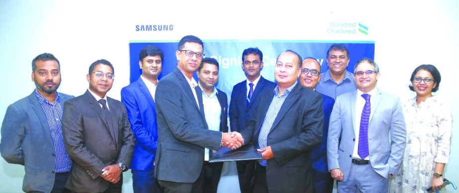 Md. Mahiul Islam, Head of Retail Products and Segments of Standard Chartered Bank and Md. Muyeedur Rahman, Head of Samsung Mobile Bangladesh, exchanging a MoU signing document at the Bank's head office in the city recently. Senior officials from respecti