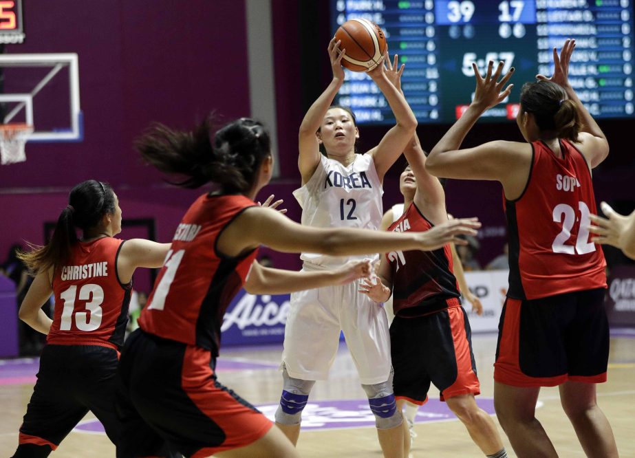 Combined Koreas Ro Suk Yong, centre, looks for support as Indonesian players attempt to block her throw during their women's basketball match at the 18th Asian Games in Jakarta, Indonesia on Wednesday.