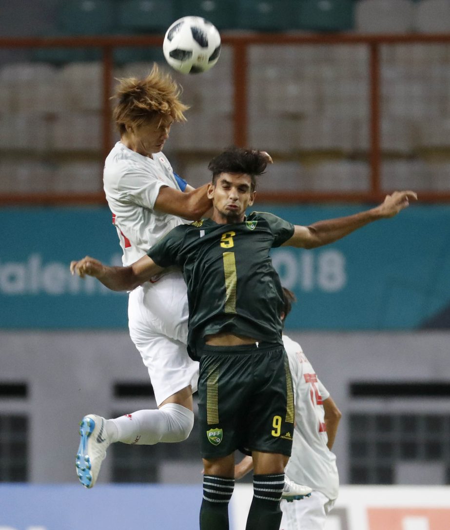 Japan's Kou Itakura leaps above Pakistan's Yousaf Ahmad to head the ball during their men's soccer match at the 18th Asian Games at Wibawa Mukti stadium in Cikarang, Indonesia on Thursday.