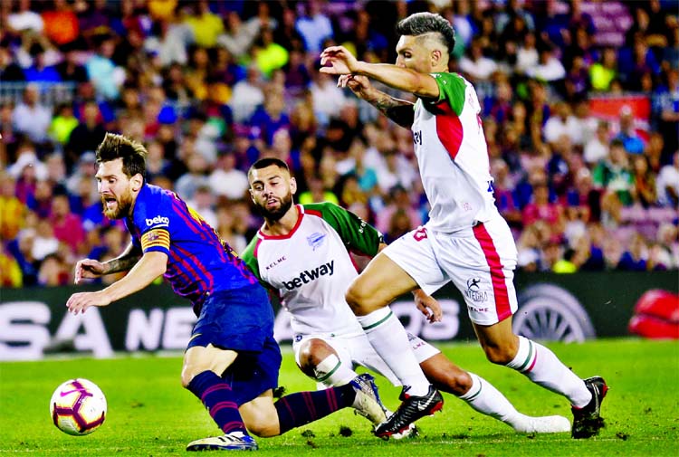 FC Barcelona's Lionel Messi (left) is tacked by Alaves' Ruben Duarte (second from left) during a Spanish La Liga soccer match at Camp Nou stadium in Barcelona, Spain on Saturday.