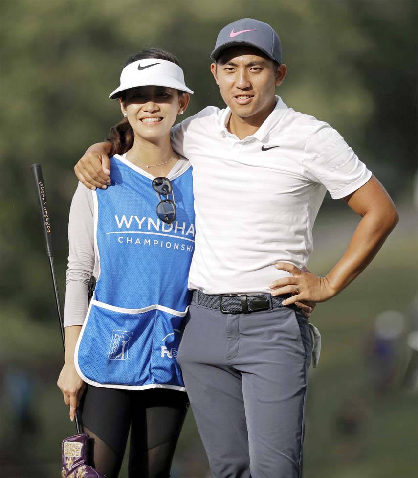C.T. Pan (right) puts his arm around his wife and caddie Michelle Lin (left) on thew 18th hole during the final round of the Wyndham Championship golf tournament at Sedgefield Country Club in Greensboro, N.C. on Sunday.