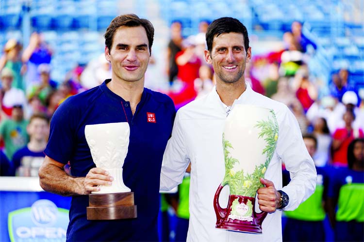 Novak Djokovic (right) of Serbia, holds the Rookwood Cup after defeating Roger Federer (left) of Switzerland, during the finals at the Western & Southern Open tennis tournament in Mason, Ohio on Sunday.
