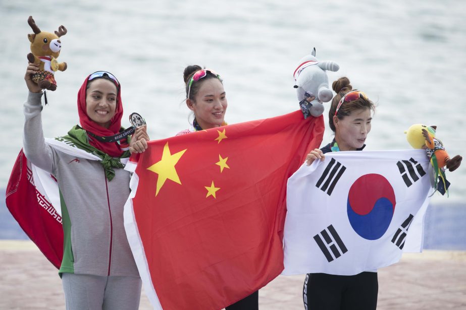 Gold medallist Li Yue of China (left) silver medallist Hediye Kazemi of Iran (right) and bronze medallist Lee Sun-ja of South Korea, right, celebrate during awards ceremony for the women's kayak single 500m at the 18th Asian Games in Palembang, Indonesia