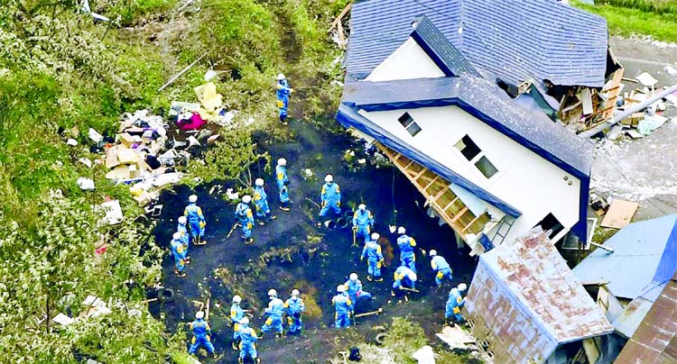 Police officers search for survivors from a house damaged by a landslide caused by an earthquake in Atsuma town, Hokkaido, northern Japan, in this photo taken by Kyodo on September 7, 2018.