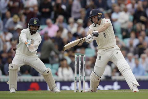 England's Jos Buttler hits a shot next to India wicketkeeper Rishabh Pant during the fifth cricket test match of a five match series between England and India at the Oval cricket ground in London on Saturday.