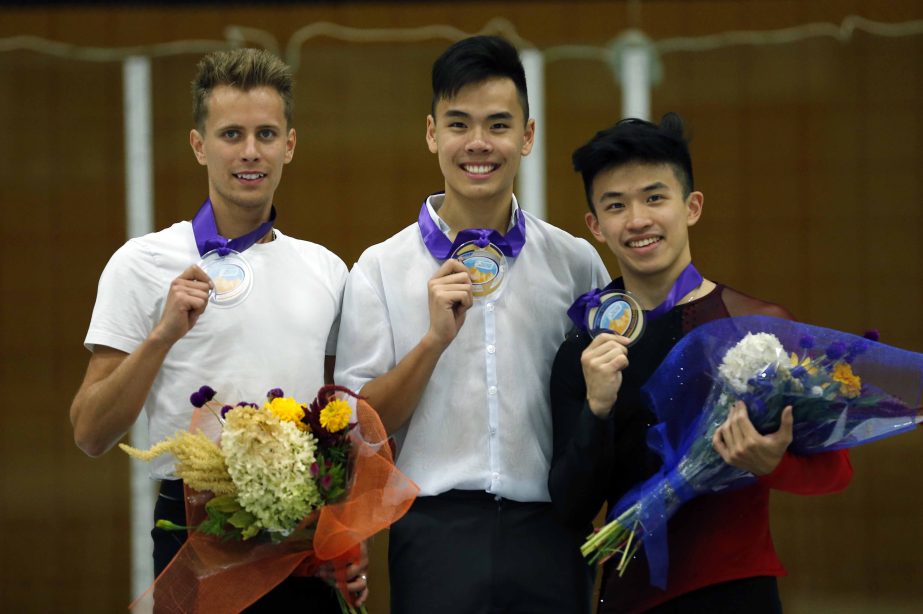 Men's first place finisher Nam Nguyen (center) of Canada, shares the podium with second place finisher Michal Brezina (left) of Czech Republic and third place finisher Jimmy Ma of the United States, following the men's free skate at the U.S. Internation