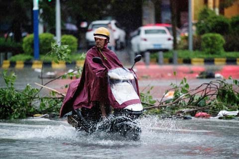 A man drives his motorbike through partially flooded streets a day after super Typhoon Mangkhut in Yangjiang, in Guangdong province