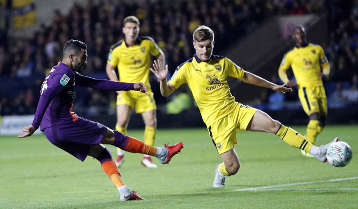 Manchester City's Riyad Mahrez, and Oxford's Luke Garbutt (right) challenge for the ball during the English League Cup soccer match between Oxford United and Manchester City at the Kassam Stadium in Oxford, England on Tuesday.