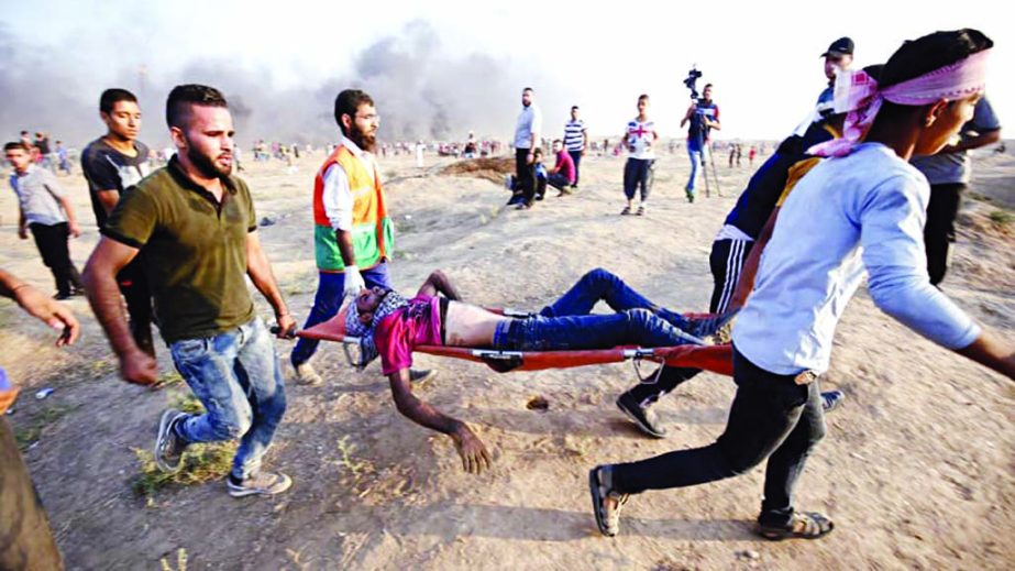 Demonstrators carry an injured Palestinian during clashes along the Israeli border fence, east of Gaza City.