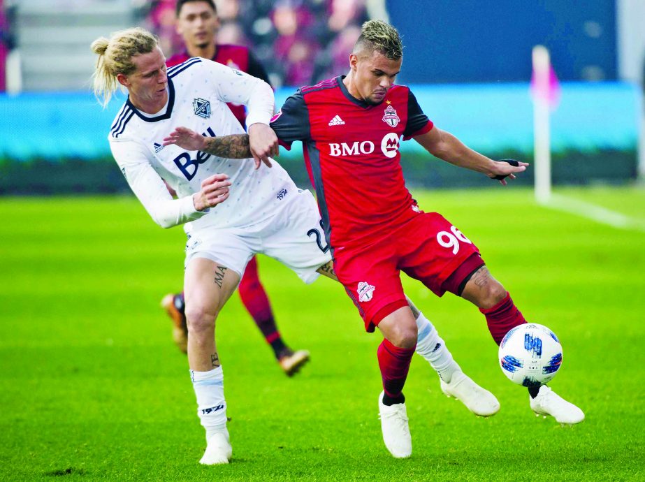 Toronto FC defender Auro (96) battles for the ball against Vancouver Whitecaps midfielder Brek Shea (20) during the first half of an MLS soccer game in Toronto, on Saturday.