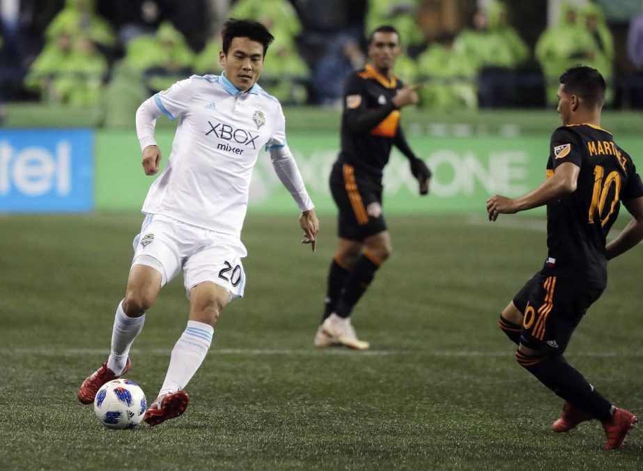 Seattle Sounders defender Kim Kee-Hee (left) dribbles the ball as Houston Dynamo midfielder Tomas Martinez (right) closes in during the second half of an MLS soccer match in Seattle on Monday. The Sounders won 4-1.