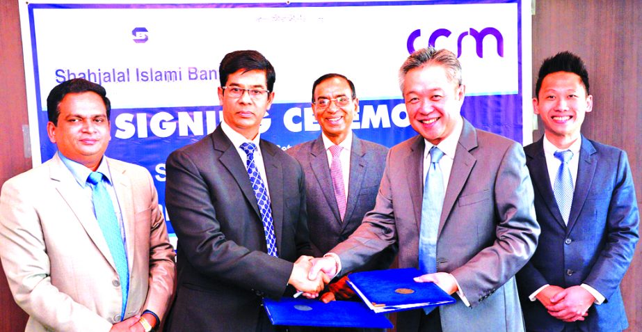 M Akhter Hossain, DMD of Shahjalal Islami Bank Limited and TAN Kah Chye, Chairman and Founder of CCR Manager Pvt Limited, Singapore exchanging an agreement signing documents at the Bank's head office in the city recently. Under the deal, customers of the