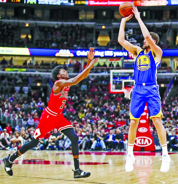 Golden State Warriors guard Klay Thompson (right) shoots a three pointer against Chicago Bulls forward Justin Holiday (left) during the first half of an NBA basketball game in Chicago on Monday.