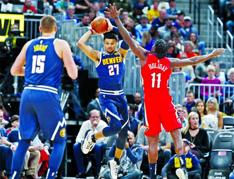 Denver Nuggets guard Jamal Murray (center) looks to pass the ball to center Nikola Jokic (left) as New Orleans Pelicans guard Jrue Holiday defends in the first half of an NBA basketball game in Denver on Monday.