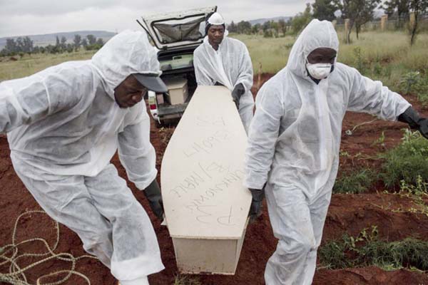 Mortuary workers carry the coffin of an unidentified migrant for burial at a cemetery outside Johannesburg. At least five bodies of unidentified people are buried on top of each other in each grave.