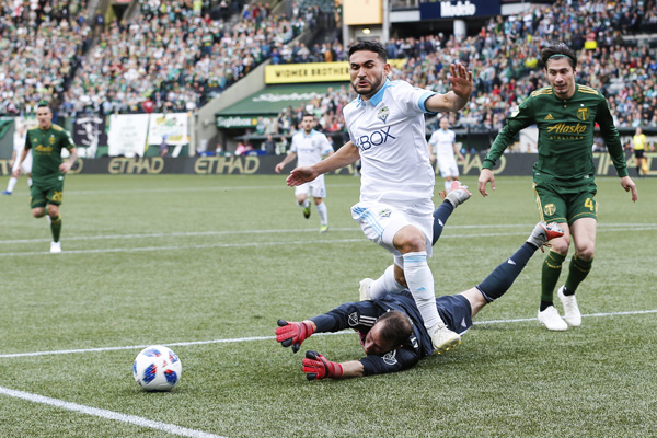 Seattle Sounders' Cristian Roldan (top center) trips over the arms of Portland Timbers goalkeeper Jeff Attinella during an MLS soccer game in the Western Conference semifinals in Portland, Ore. on Sunday.