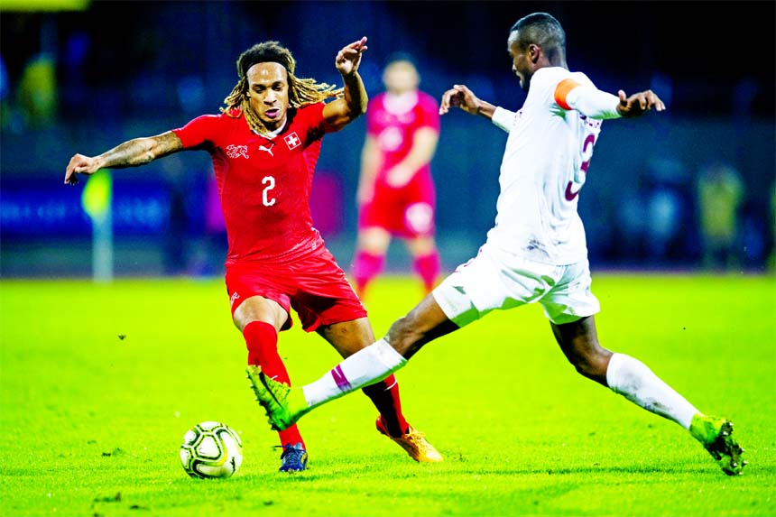 Switzerland's Kevin Mbabu (left) is challenged by Qatar's Abdelkarim Hassan during an international friendly soccer match between Switzerland and Qatar at the Cornaredo stadium in Lugano, Switzerland on Wednesday.