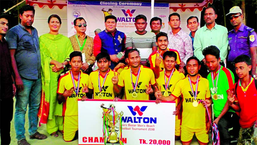 Youngmen's Club, the champions of the Walton 5th Men's Beach Football Tournament with the guests and officials of Cox's Bazar District Sports Association pose for a photo session at the Suganda Point in Cax's Bazar Sea Beach on Thursday.