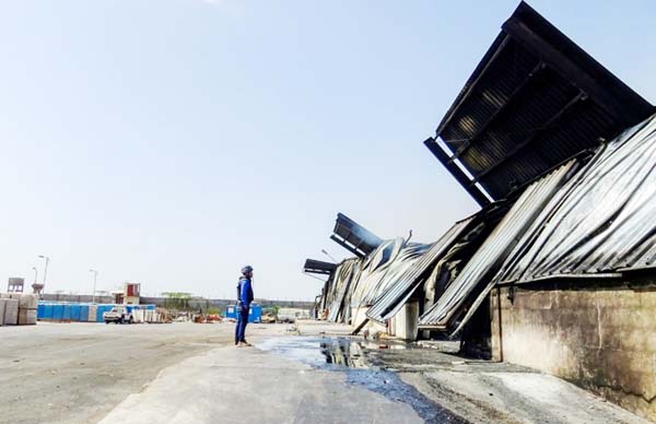 A journalist looks at a destroyed warehouse in an industrial district in the eastern outskirts of the Yemeni port city of Hodeida