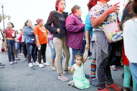 Central American migrants, as part of the Central American caravan trying to reach the United States, wait to receive donated dinner downtown in Mexicali, Mexico on Monday.