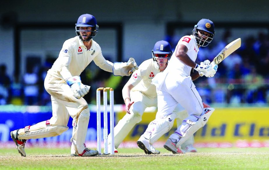 Sri Lanka's Dimuth Karunaratne, right plays a shot as England's wicketkeeper Ben Foakes and fielder Keaton Jennings watch during the second day of the third test cricket match between Sri Lanka and England, in Colombo, Sri Lanka on Saturday.