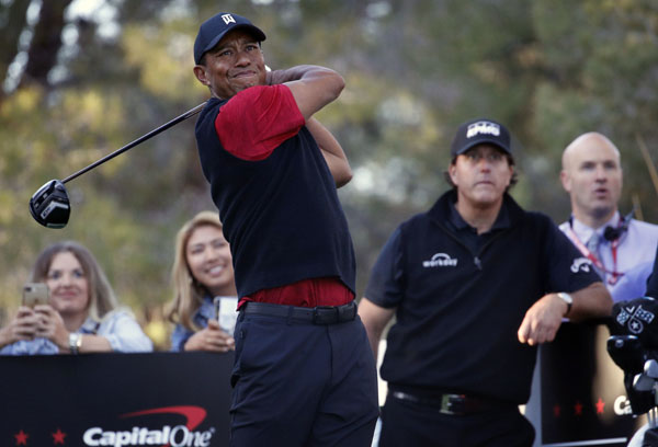 Tiger Woods hits off the 16th tee as Phil Mickelson watches during a golf match at Shadow Creek golf course in Las Vegas on Friday.