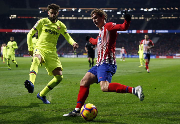 Barcelona's Gerard Pique (left) tries to block a shot from Atletico's Antoine Griezmann during a Spanish La Liga soccer match between Atletico Madrid and FC Barcelona at the Metropolitano stadium in Madrid on Saturday.