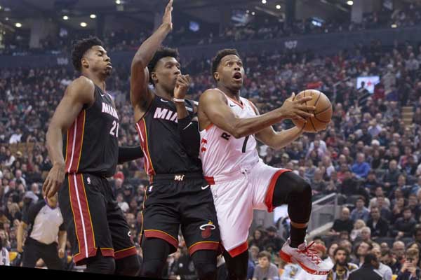 Toronto Raptors guard Kyle Lowry (right) shoots on Miami Heat's Josh Richardson, center, and Hassan Whiteside during first half NBA basketball action in Toronto on Sunday.