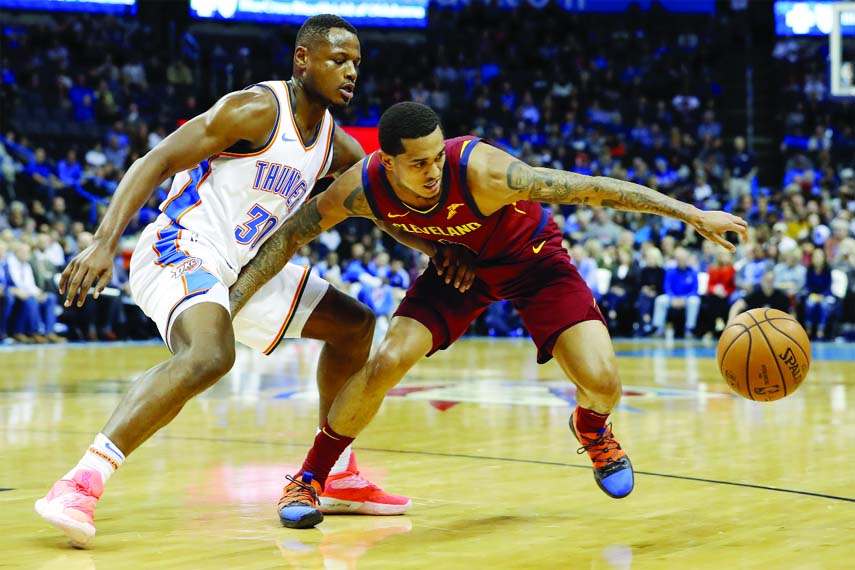 Cleveland Cavaliers guard Jordan Clarkson (8) works to reach a loose ball as Oklahoma City Thunder guard Deonte Burton (30) defends during the first half of an NBA basketball game in Oklahoma City on Wednesday.