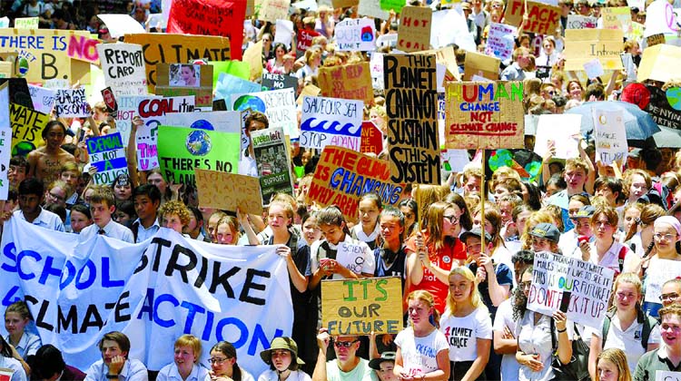 Thousands of children hold placards and chant slogans after they walked out of school in protest against government inaction on climate change in Sydney in Australia on Friday.