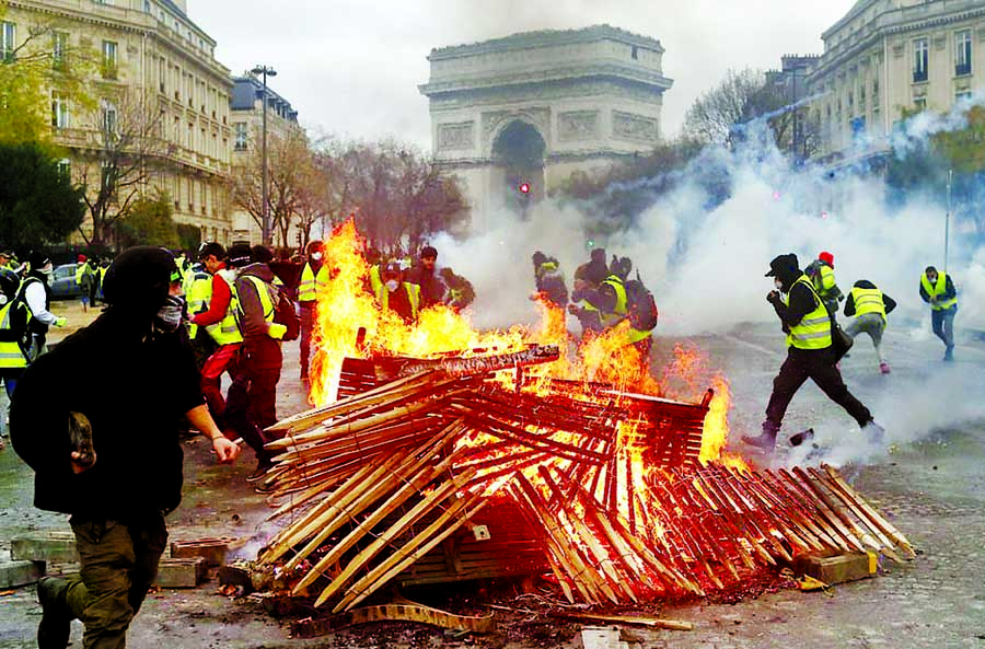 Demonstrators run by a burning fire near the Arc de Triomphe during a fresh protest which has seen Yellow Vest supporters clash with riot police and more than 100 people arrested so far on Saturday Internet photo