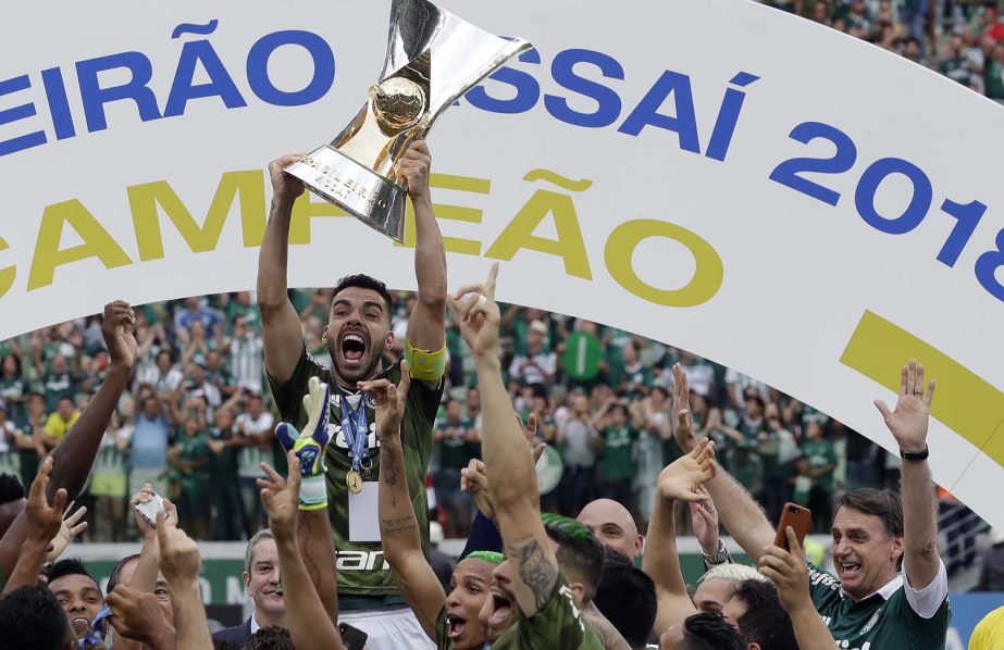 Palmeiras' Bruno Henrique holds up the trophy as he celebrates with teammates and Brazil's President-elect Jair Bolsonar ( right) after Palmeiras defeated Vitoria and clenched Brazil's soccer championship in Sao Paulo, Brazil on Sunday.