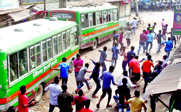 Garment workers being chased by the police while they were brick batting on buses, demanding arrears and dues at BSCIC area in N'ganj on Monday.