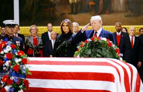 US President Donald J. Trump, with First Lady Melania Trump, salutes the casket containing the body of former US President George H.W. Bush in the Rotunda of the US Capitol in Washington, DC on Monday.