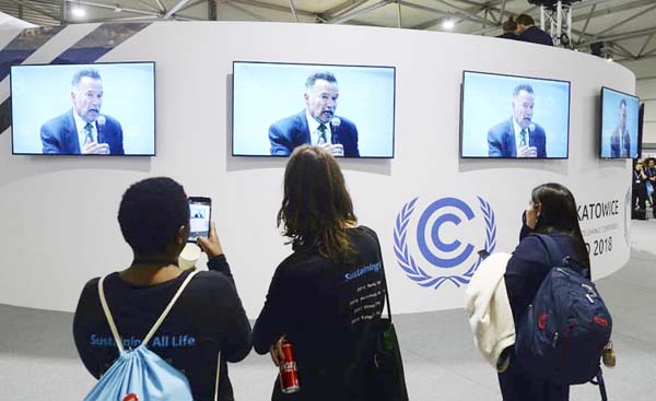 Visitors to the UN climate conference watch a speech by Arnold Schwarzenegger, in Katowice, Poland on Monday.