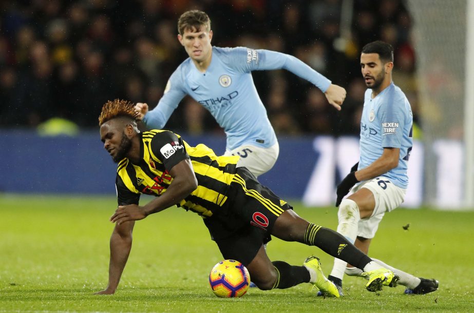 Watford's Isaac Success (bottom) challenges for the ball with Manchester City's John Stones (top left) and Manchester City's Riyad Mahrez during the English Premier League soccer match between Watford and Manchester City at Vicarage Road stadium in