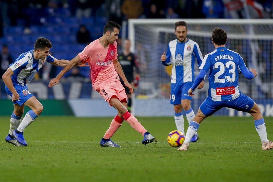 FC Barcelona midfielder Sergio Busquets (center) kicks the ball through RCD Espanyol forward Granero (23) during the Spanish La Liga soccer match between Espanyol and FC Barcelona at RCDE stadium in Cornella Llobregat, Spain on Saturday.