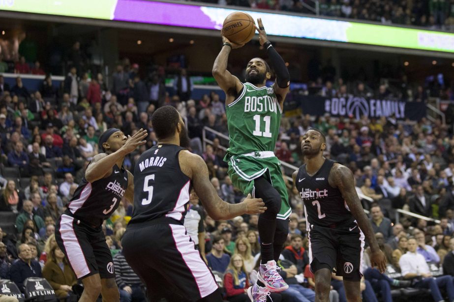 Boston Celtics guard Kyrie Irving (11) shoots between Washington Wizards guard Bradley Beal (3), forward Markieff Morris (5), and guard John Wall (2) during the overtime period of an NBA basketball game on Wednesday in Washington.