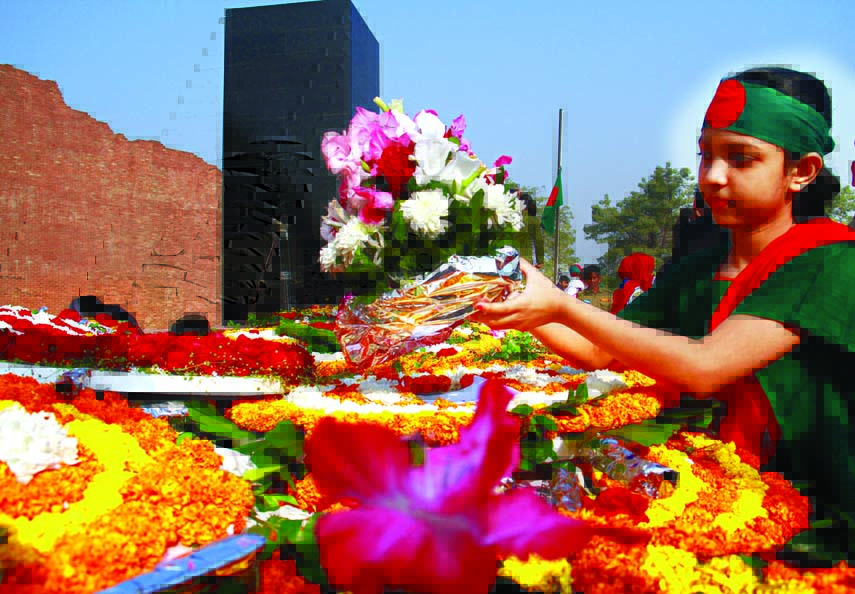 A tiny girl wearing national flag as headgear placing wreaths at the Martyred Intellectuals Memorial at Mirpur on Friday.