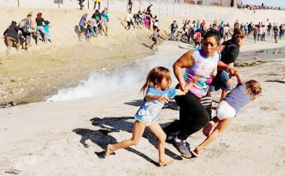 A migrant family traveling from Central America en route to the US run away from tear gas.