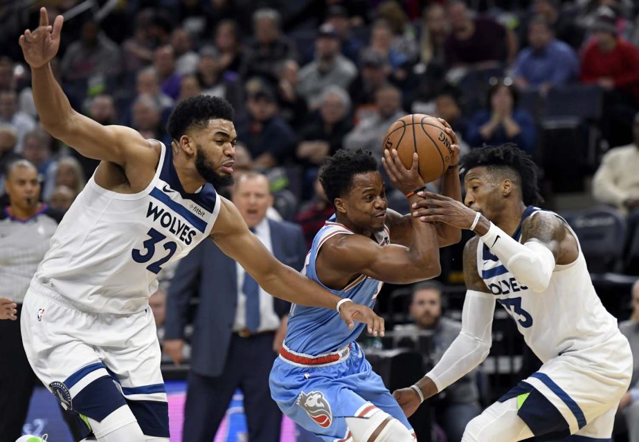 Minnesota Timberwolves' Robert Covington (33) fouls Sacramento Kings' Yogi Ferrell (3) as Minnesota Timberwolves' Karl-Anthony Towns (32) helps guard during the third quarter of an NBA basketball game on Monday.