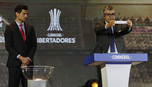 Conmebol Competition Secretary Fred Nantes holds up the name of Brazil's Flamengo during the drawing ceremony for the Copa Libertadores soccer tournament in Luque, Paraguay on Monday. At left is Paraguay's soccer player Roque Santa Cruz.
