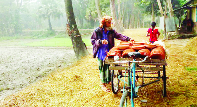 NOAKHALI: A pottery trader carrying his goods at Lalpur area as pottery goods are still in demand during his winter season for pithas making. This snap was taken yesterday.