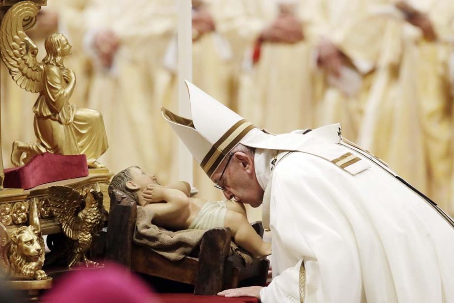 Pope Francis kisses a statue of Baby Jesus as he celebrates the Christmas Eve Mass in St. Peter's Basilica at the Vatican on Monday.
