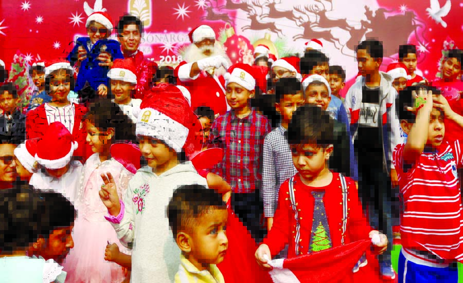 Santa Claus distributing chocolates among the children on the occasion of holy Christmas. The snap was taken from the city's Sonargaon Hotel on Tuesday.